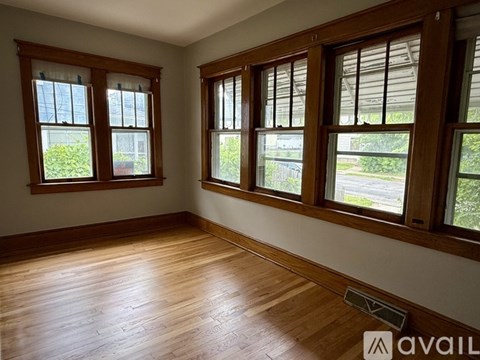 A room with wooden floors and three windows.