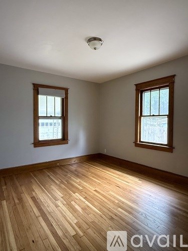 A room with wooden floors and two windows.