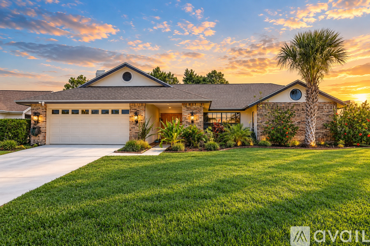 A house with a driveway and a palm tree in front.