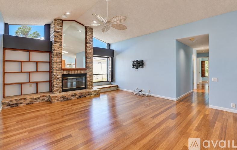 A spacious room with a fireplace and wood flooring.