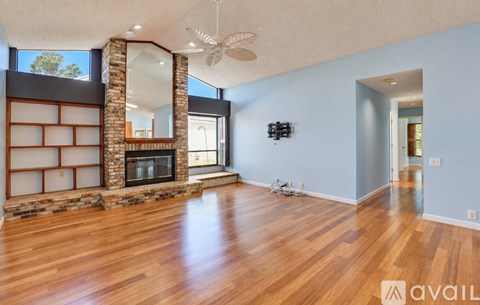 A spacious room with a fireplace and wood flooring.
