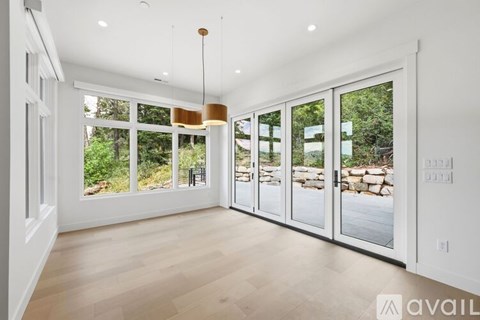 A spacious room with a view of a garden through the sliding glass doors.