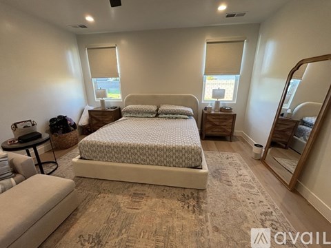 A bedroom with a large bed, a bench, and a dresser.