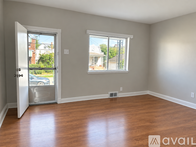 A room with wooden floors and a window overlooking a street.