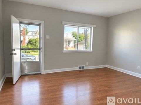 A room with wooden floors and a window overlooking a street.