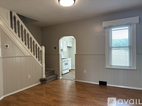 A room with wooden floors and a staircase leading to the upper level.
