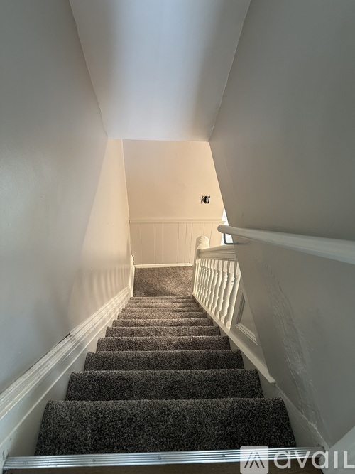 A staircase with a carpeted runner and white walls.