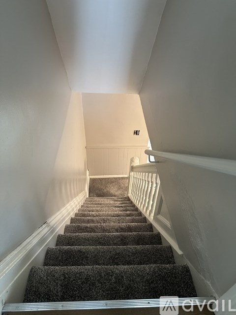 A staircase with a carpeted runner and white walls.