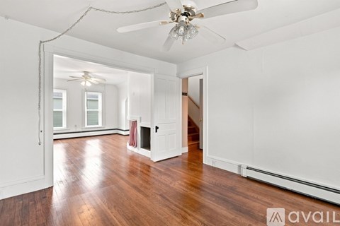 A spacious room with wooden floors and a ceiling fan.