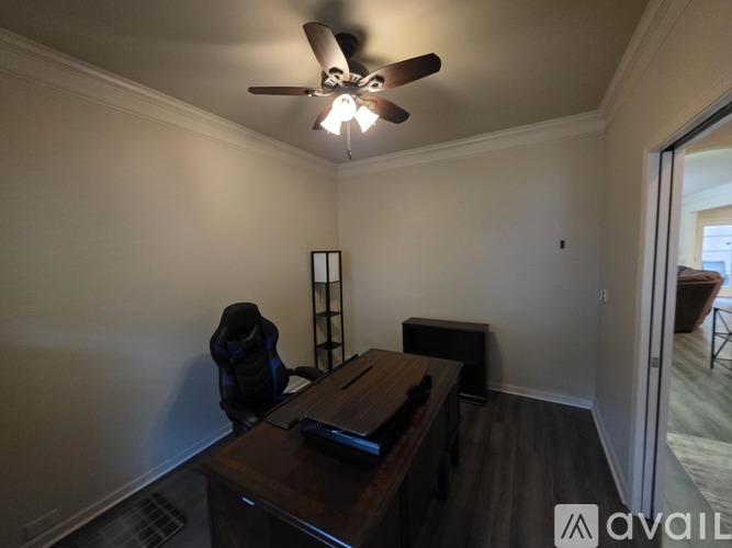 A room with a ceiling fan and a brown desk.