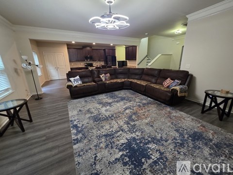 A living room with a brown sofa and a rug.