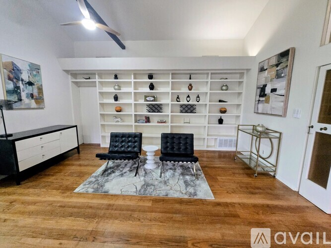 A living room with a black chair and a white shelf with various items on it.