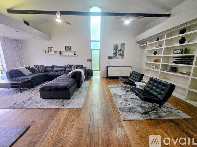 A living room with a black couch and a wooden floor.