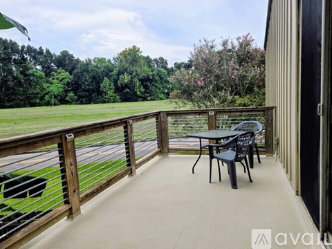 A balcony with a table and chairs overlooking a grassy field.