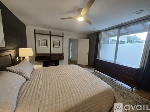 A bedroom with a large bed and a ceiling fan.