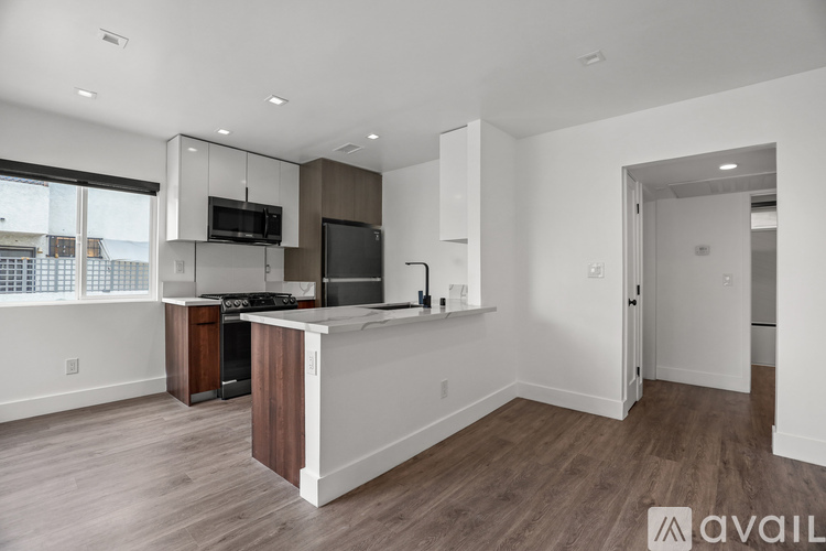 A modern kitchen with white walls and wooden floors.
