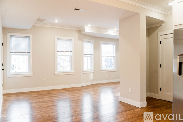 A spacious room with wooden floors and three windows.