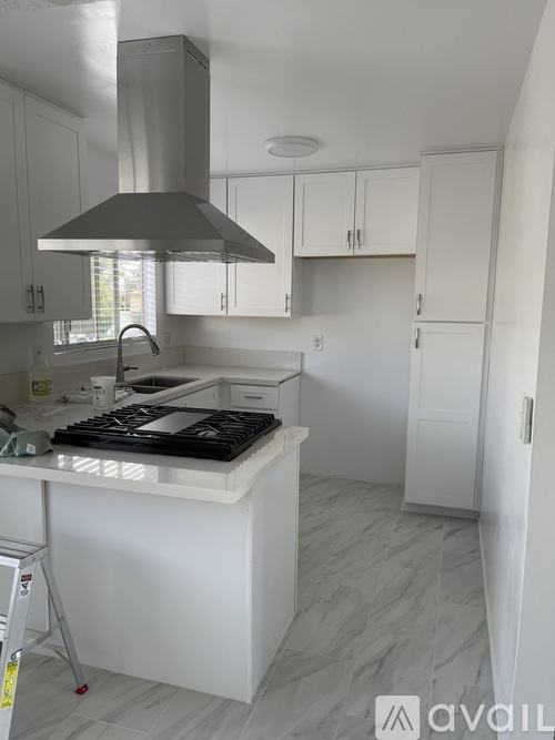 A modern kitchen with a white island and stove top.