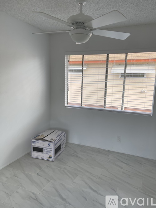 A room with a ceiling fan and a window with blinds.