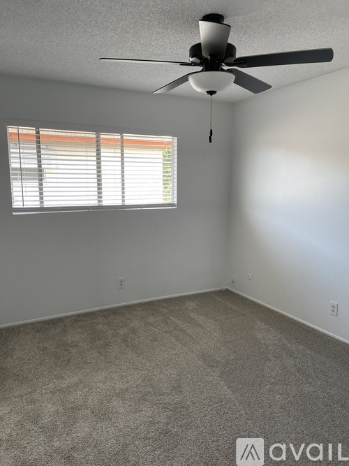 A room with a ceiling fan and a window with blinds.