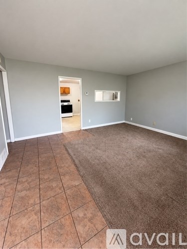 A room with a brown rug and tile floor.
