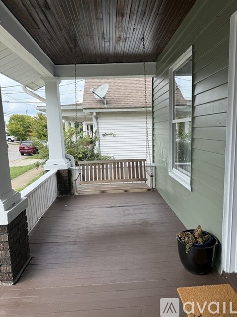 A porch with a wooden floor and a white railing.