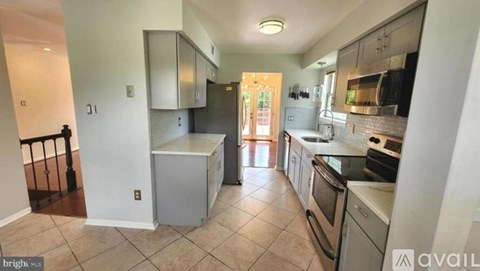 A kitchen with white appliances and a tiled floor.
