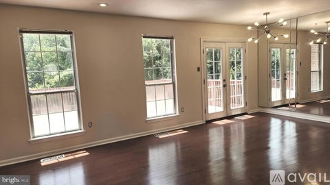 A spacious room with wooden floors and large windows.