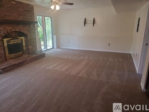 A living room with a fireplace and a ceiling fan.