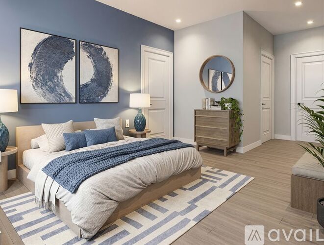 A bedroom with a large bed and a blue and white striped rug.