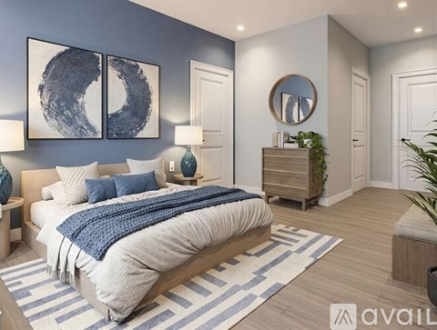 A bedroom with a large bed and a blue and white striped rug.