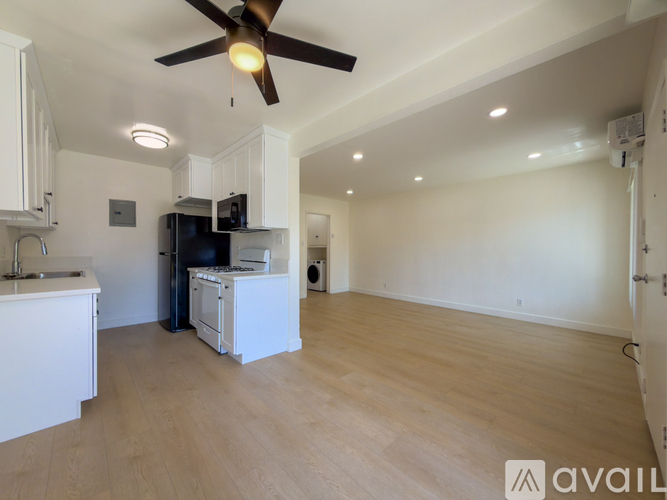 A kitchen with white cabinets and a black fridge is shown.