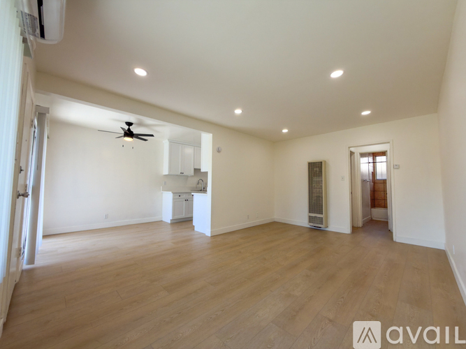 A spacious room with wooden floors and a ceiling fan.