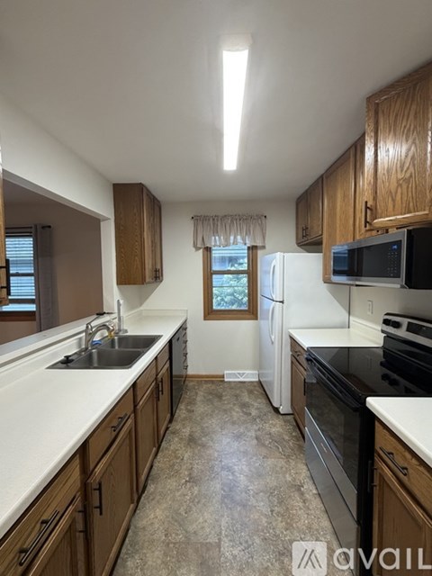 A kitchen with wooden cabinets and a window with a view of trees.