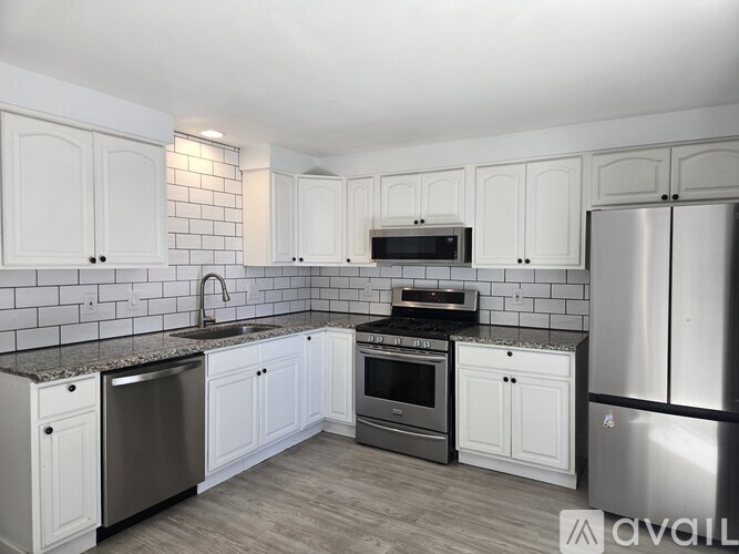A kitchen with white cabinets and a black and white tiled backsplash.