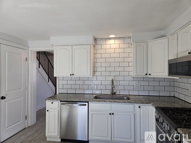 A kitchen with white cabinets and a black countertop.