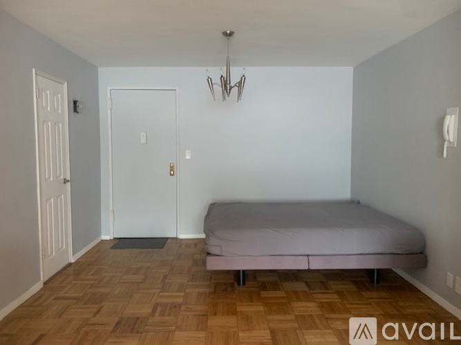 A bedroom with a bed, two doors, and a chandelier.
