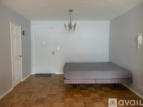 A bedroom with a bed, two doors, and a chandelier.