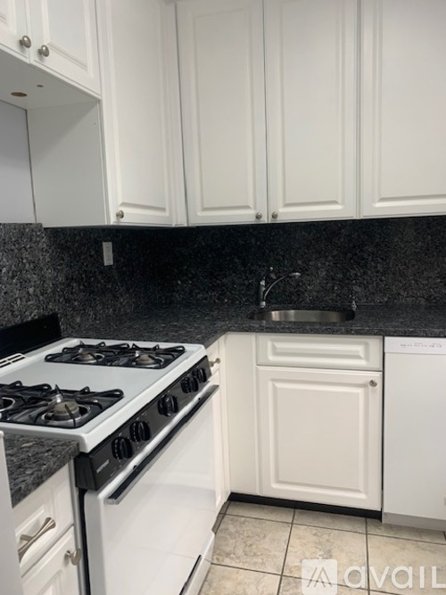 A kitchen with a white stove and cabinets.