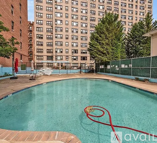 A pool with a red hose in it and apartment buildings in the background.