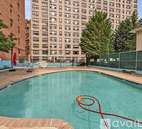 A pool with a red hose in it and apartment buildings in the background.