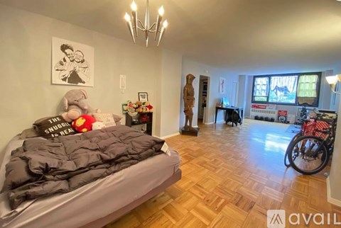 A bedroom with a bed, a bicycle, and a chandelier.