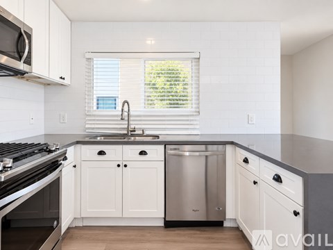 A kitchen with white cabinets and a stainless steel dishwasher.