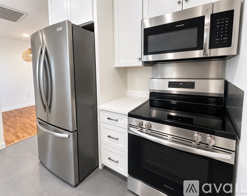 A kitchen with a stainless steel refrigerator and an oven with a microwave above it.