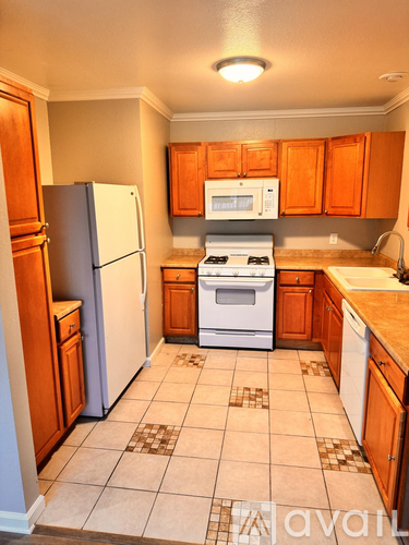 A kitchen with a white refrigerator, white stove, and brown cabinets.