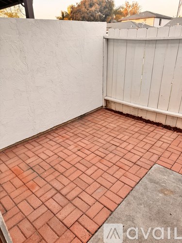 A patio with red tiles and a white wall.