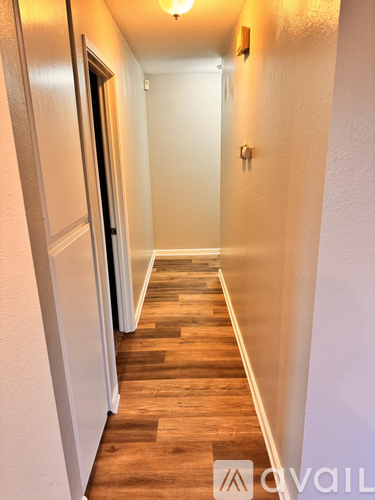 A hallway with wooden floors and white walls.