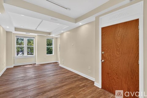 A room with wooden floors and a door leading to another room.