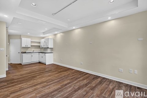 A spacious kitchen with white cabinets and a wooden floor.