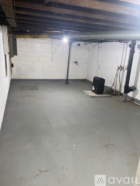 A basement with a concrete floor and a white wall.